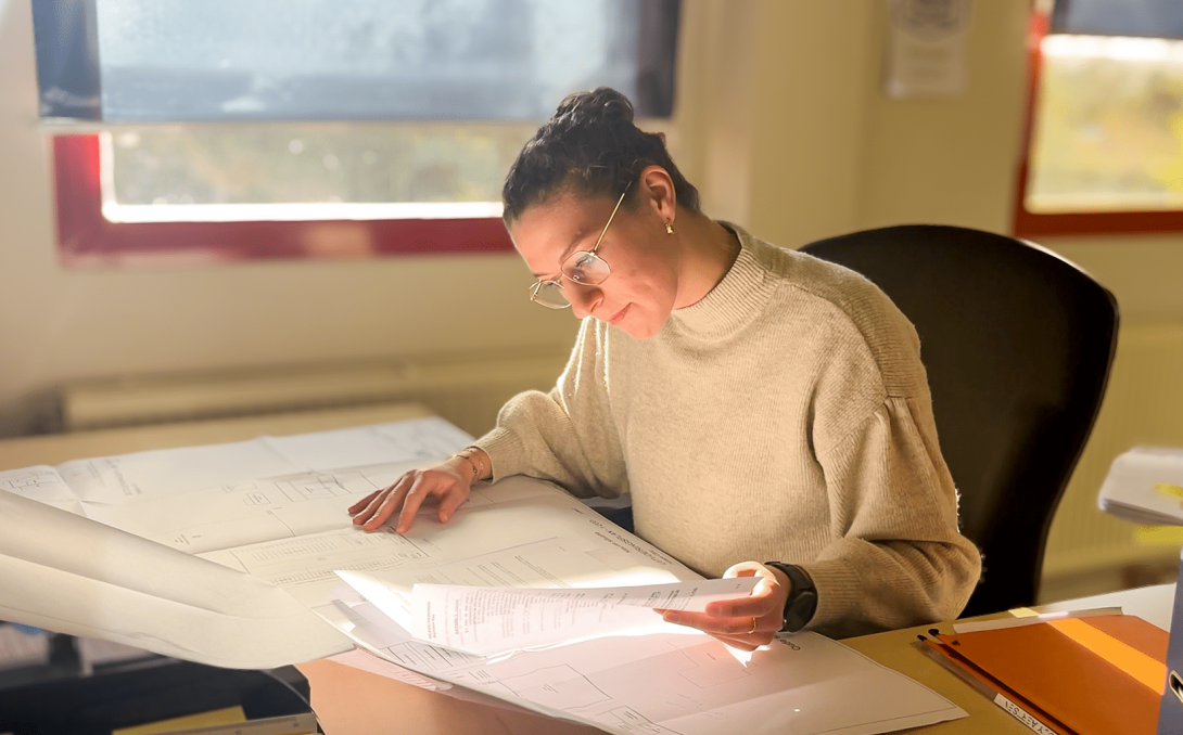 Collega Ilse leest plannen aan bureau